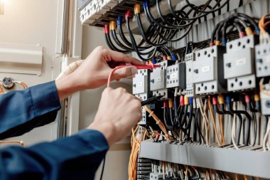 Elektrik mühendisi elektrik sistemi kontrol dolabındaki elektrik akımını ve elektrik hattını test etmek için çoklu metre kullanıyor..