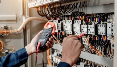 Elektrik mühendisi elektrik sistemi kontrol dolabındaki elektrik akımını ve elektrik hattını test etmek için çoklu metre kullanıyor..
