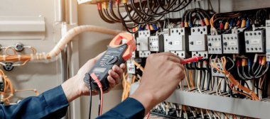 Elektrik mühendisi elektrik sistemi kontrol dolabındaki elektrik akımını ve elektrik hattını test etmek için çoklu metre kullanıyor..