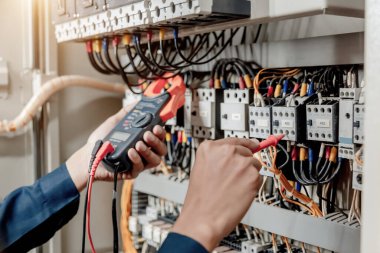 Elektrik mühendisi elektrik sistemi kontrol dolabındaki elektrik akımını ve elektrik hattını test etmek için çoklu metre kullanıyor..
