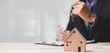 Buy or Rent 'le çalışan iş adamı, kopyalama alanı. Mülk yatırımı ve ev kredisi finansal konsepti El 'in ahşap eve para yığını koyması..