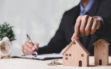 Buy or Rent 'le çalışan iş adamı, kopyalama alanı. Mülk yatırımı ve ev kredisi finansal konsepti El 'in ahşap eve para yığını koyması..