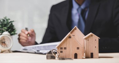 Buy or Rent 'le çalışan iş adamı, kopyalama alanı. Mülk yatırımı ve ev kredisi finansal konsepti El 'in ahşap eve para yığını koyması..