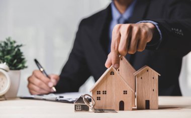Buy or Rent 'le çalışan iş adamı, kopyalama alanı. Mülk yatırımı ve ev kredisi finansal konsepti El 'in ahşap eve para yığını koyması..