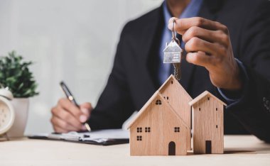 Buy or Rent 'le çalışan iş adamı, kopyalama alanı. Mülk yatırımı ve ev kredisi finansal konsepti El 'in ahşap eve para yığını koyması..