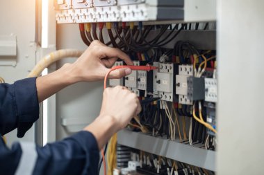 Elektrik mühendisi elektrik kabinesi kontrolündeki voltaj ve elektrik akımını ölçen bir testçi, elektrik sisteminin işleyişini konsept olarak kontrol ediyor .