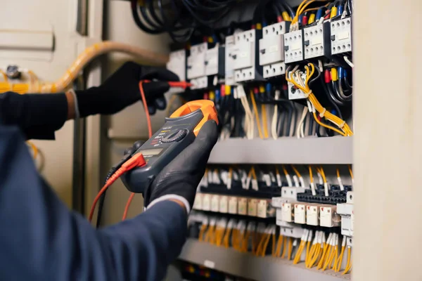電気技師は 電気キャビネット制御の電力線の電圧と電流を測定し リレー保護システムのワイヤを測定します コントロール ユニット 中電圧開閉装置 — ストック写真