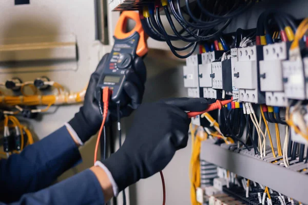 Elektrik mühendisi, elektrik kabinesi kontrolündeki voltaj ve elektrik akımını ölçen bir testçi ve röle koruma sistemindeki kabloları kontrol ediyor. Körfez kontrol birimi. Orta gerilim şalteri.