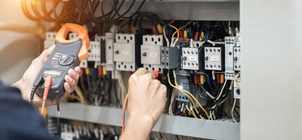 Elektrik mühendisi elektrik kabinesi kontrolündeki voltaj ve elektrik akımını ölçen bir testçi, elektrik sisteminin işleyişini konsept olarak kontrol ediyor .