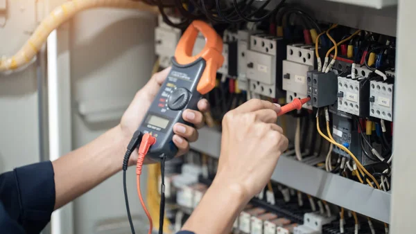 Elektrik mühendisi elektrik kabinesi kontrolündeki voltaj ve elektrik akımını ölçen bir testçi, elektrik sisteminin işleyişini konsept olarak kontrol ediyor .