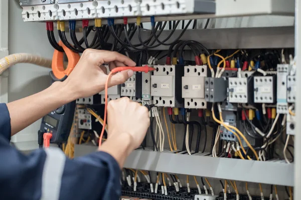 Electrician engineer work tester measuring voltage and current of power electric line in electical cabinet control , concept check the operation of the electrical system .