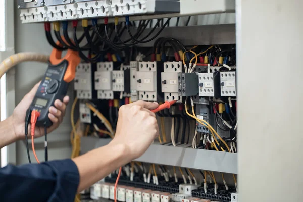 Elektrik mühendisi elektrik kabinesi kontrolündeki voltaj ve elektrik akımını ölçen bir testçi, elektrik sisteminin işleyişini konsept olarak kontrol ediyor .