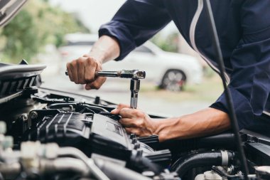 Otomobil tamircisi elleri ingiliz anahtarı, araba servisi ve bakımı ile bir araba motoru otomotiv atölyesini tamir ediyor..