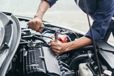 Otomobil tamircisi elleri ingiliz anahtarı, araba servisi ve bakımı ile bir araba motoru otomotiv atölyesini tamir ediyor..