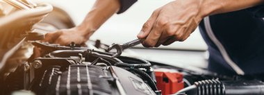 Otomobil tamircisi elleri ingiliz anahtarı, araba servisi ve bakımı ile bir araba motoru otomotiv atölyesini tamir ediyor..