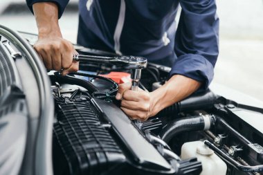 Otomobil tamircisi elleri ingiliz anahtarı, araba servisi ve bakımı ile bir araba motoru otomotiv atölyesini tamir ediyor..