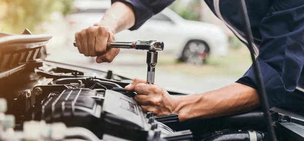 Otomobil tamircisi elleri ingiliz anahtarı, araba servisi ve bakımı ile bir araba motoru otomotiv atölyesini tamir ediyor..