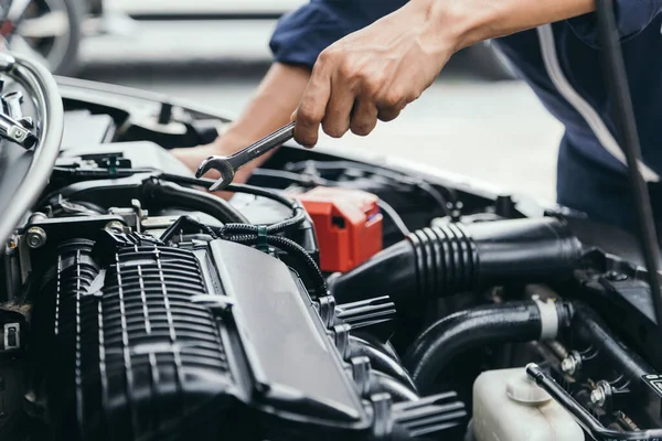 Otomobil tamircisi elleri ingiliz anahtarı, araba servisi ve bakımı ile bir araba motoru otomotiv atölyesini tamir ediyor..