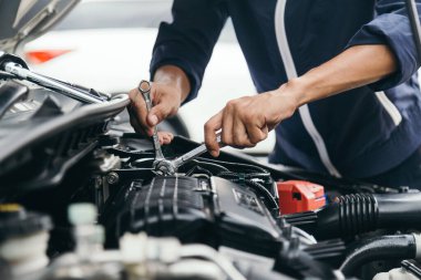 Otomobil tamircisi elleri ingiliz anahtarı, araba servisi ve bakımı ile bir araba motoru otomotiv atölyesini tamir ediyor..