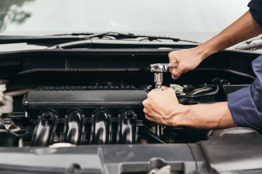 Otomobil tamircisi elleri ingiliz anahtarı, araba servisi ve bakımı ile bir araba motoru otomotiv atölyesini tamir ediyor..