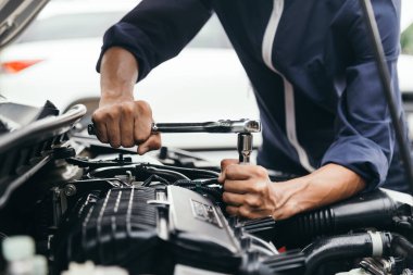 Otomobil tamircisi elleri ingiliz anahtarı, araba servisi ve bakımı ile bir araba motoru otomotiv atölyesini tamir ediyor..