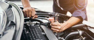 Otomobil tamircisi elleri ingiliz anahtarı, araba servisi ve bakımı ile bir araba motoru otomotiv atölyesini tamir ediyor..