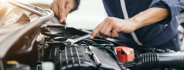 Otomobil tamircisi elleri ingiliz anahtarı, araba servisi ve bakımı ile bir araba motoru otomotiv atölyesini tamir ediyor..