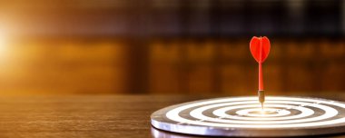 Kırmızı dart oku hedef tahtanın ortasına güneş ışığı klasik tarzıyla vuruyor, hedef pazarlama ve ticari başarı kavramı .