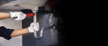 Tesisatçı ayarlanabilir anahtarla beyaz lavabo borusunu tamir ediyor..