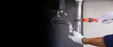 Tesisatçı ayarlanabilir anahtarla beyaz lavabo borusunu tamir ediyor..