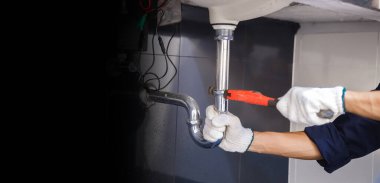 Tesisatçı ayarlanabilir anahtarla beyaz lavabo borusunu tamir ediyor..