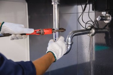 Tesisatçı ayarlanabilir anahtarla beyaz lavabo borusunu tamir ediyor..