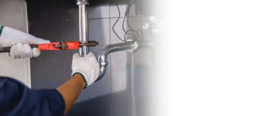 Tesisatçı ayarlanabilir anahtarla beyaz lavabo borusunu tamir ediyor..