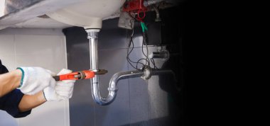 Tesisatçı ayarlanabilir anahtarla beyaz lavabo borusunu tamir ediyor..