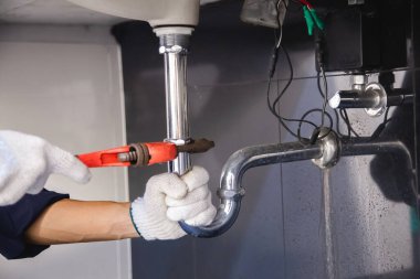 Tesisatçı ayarlanabilir anahtarla beyaz lavabo borusunu tamir ediyor..