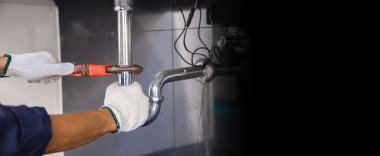 Tesisatçı ayarlanabilir anahtarla beyaz lavabo borusunu tamir ediyor..