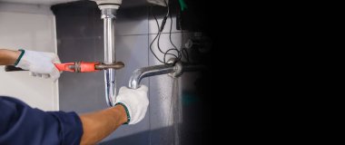 Tesisatçı ayarlanabilir anahtarla beyaz lavabo borusunu tamir ediyor..