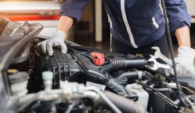 Otomobil tamircisi elleri ingiliz anahtarı, araba servisi ve bakımı ile bir araba motoru otomotiv atölyesini tamir ediyor..