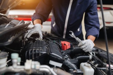 Otomobil tamircisi elleri ingiliz anahtarı, araba servisi ve bakımı ile bir araba motoru otomotiv atölyesini tamir ediyor..