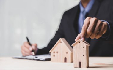 Buy or Rent 'le çalışan iş adamı, kopyalama alanı. Mülk yatırımı ve ev kredisi finansal konsepti El 'in ahşap eve para yığını koyması..