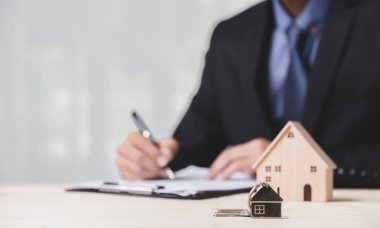 Buy or Rent 'le çalışan iş adamı, kopyalama alanı. Mülk yatırımı ve ev kredisi finansal konsepti El 'in ahşap eve para yığını koyması..