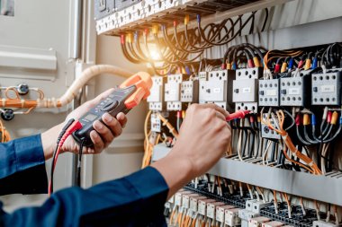 Elektrik mühendisi elektrik sistemi kontrol dolabındaki elektrik akımını ve elektrik hattını test etmek için çoklu metre kullanıyor..