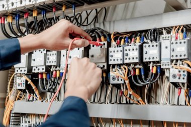 Elektrik mühendisi elektrik sistemi kontrol dolabındaki elektrik akımını ve elektrik hattını test etmek için çoklu metre kullanıyor..