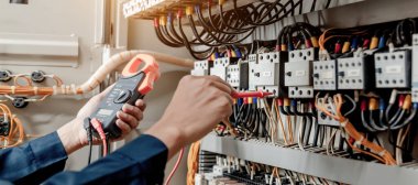 Elektrik mühendisi elektrik sistemi kontrol dolabındaki elektrik akımını ve elektrik hattını test etmek için çoklu metre kullanıyor..