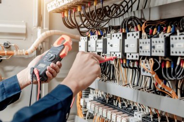 Elektrik mühendisi elektrik sistemi kontrol dolabındaki elektrik akımını ve elektrik hattını test etmek için çoklu metre kullanıyor..