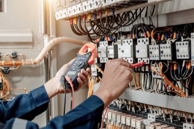 Elektrik mühendisi elektrik sistemi kontrol dolabındaki elektrik akımını ve elektrik hattını test etmek için çoklu metre kullanıyor..