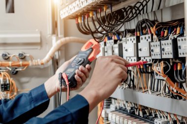 Elektrik mühendisi elektrik sistemi kontrol dolabındaki elektrik akımını ve elektrik hattını test etmek için çoklu metre kullanıyor..