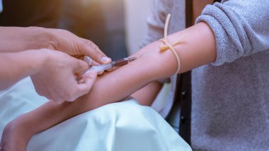 Hemşire, doktor ya da tıp teknisyeninin mavi eldivenli eli hastanedeki bir hastadan kan örneği alıyor.