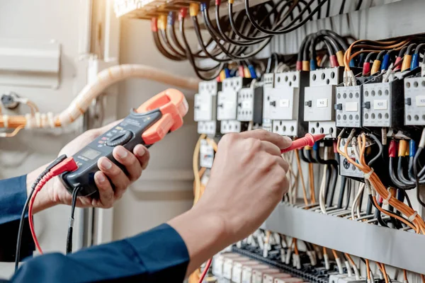 Elektrik mühendisi elektrik sistemi kontrol dolabındaki elektrik akımını ve elektrik hattını test etmek için çoklu metre kullanıyor..