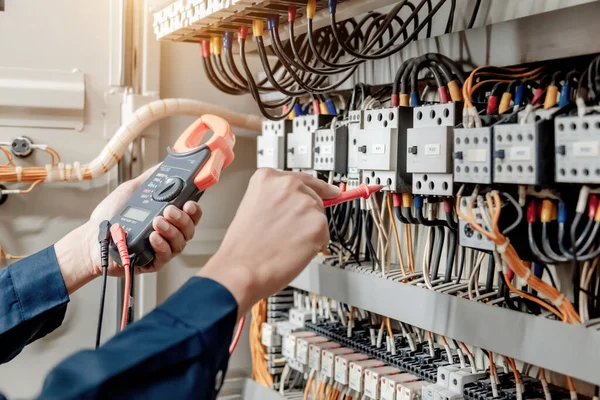 Elektrik mühendisi elektrik sistemi kontrol dolabındaki elektrik akımını ve elektrik hattını test etmek için çoklu metre kullanıyor..